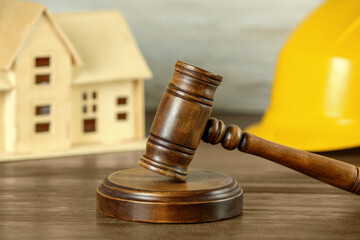 Construction and land law concepts. Judge gavel, hardhat with house model on wooden table