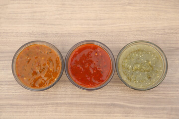 Different tasty salsa sauces on wooden table, flat lay