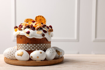 Traditional Easter cake with dried fruits and decorated eggs on white wooden table indoors. Space for text