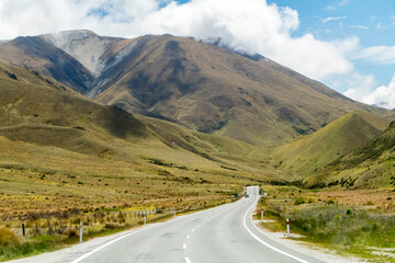 Winding and scenic road in New Zealand, with mountains and blue sky