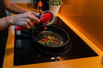 Unrecognizable person throwing vegetables in a frying pan