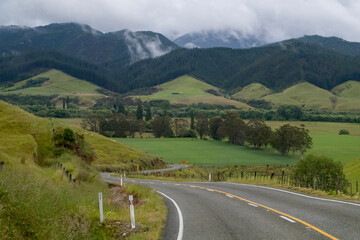 Winding and scenic road in New Zealand, with mountains and green grass