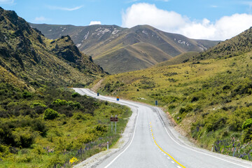 Winding and scenic road in New Zealand, with mountains and blue sky