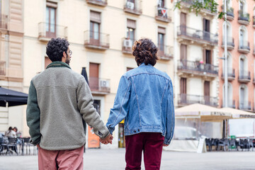 rear view of a gay male couple walking holding hands, concept of freedom and love between people of the same sex