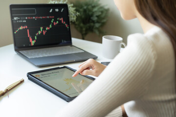 Investor analyzing exchange market asian young business woman trader on graphic charts on touchscreen, hand in using tablet for trading stock, looking at screen with diagrams at home office.