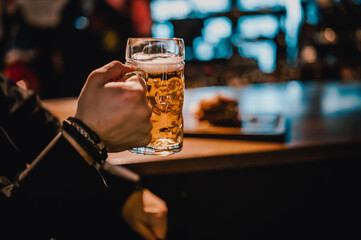 man holds a glass of beer in his hand at the bar or pub