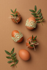 Festively decorated chicken eggs on brown background, flat lay. Happy Easter