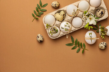 Fototapeta na wymiar Happy Easter. Festive composition with eggs and floral decor on brown background, flat lay. Space for text