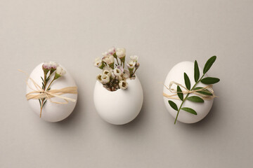Festive composition with chicken eggs and natural decor on light grey background, flat lay. Happy Easter
