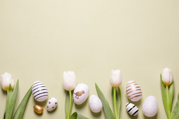Flat lay composition of painted Easter eggs and tulip flowers on light green background. Space for...