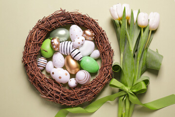 Flat lay composition of painted Easter eggs and tulip flowers on light green background