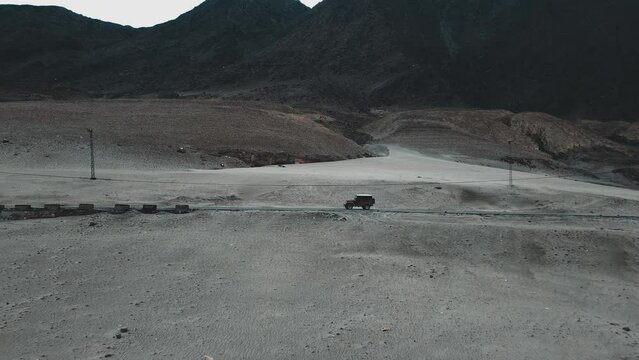 Aerial view of a jeep on Chilas Road Gilgit Baltistan Pakistan, 2 jeeps crossing each other on road. Aerial zoom-out shot of jeep on road.
