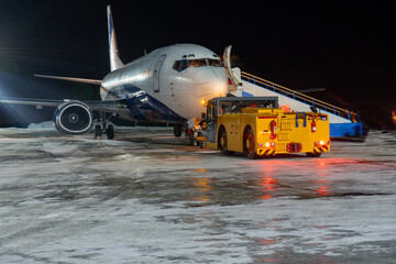 Close-up with high detail of a large wide-body passenger aircraft standing in the airport parking lot during ground handling at night