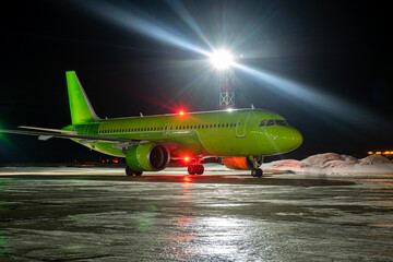 Close-up with high detail of a large wide-body passenger aircraft standing in the airport parking lot during ground handling at night