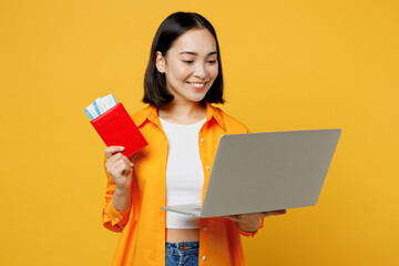 Young woman wear casual clothes use holding work passport ticket laptop pc computer isolated on plain yellow background Tourist travel abroad in free time rest getaway Air flight trip journey concept