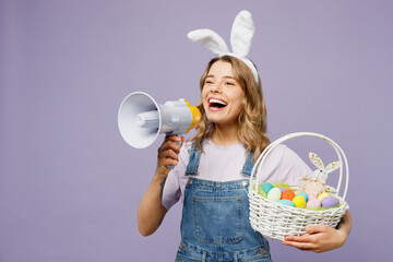 Young woman wear casual clothes bunny rabbit ears hold wicker basket colorful eggs hold megaphone...