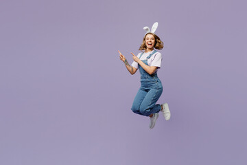 Full body young woman wear casual clothes bunny rabbit ears point finger aside indicate on workspace area copy space mock up isolated on plain pastel purple background. Lifestyle Happy Easter concept.