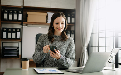 Young beautiful woman typing on tablet and laptop while sitting at the working wooden table office