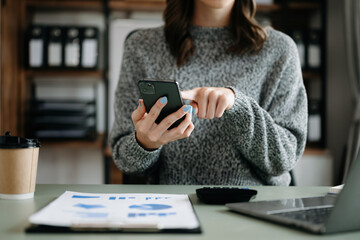 Confident businesswoman working on laptop,tablet and tablet at her workplace at modern office..