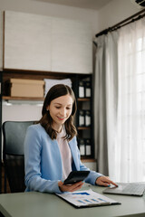 Beautiful business woman typing laptop and tablet Placed at the table at the modern office