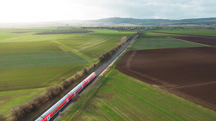 aerial view of train driving through the fields in the countryside