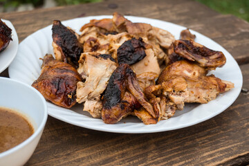 A plate of chopped Lechon Manok, or roasted chicken served outside at a bench with gravy.