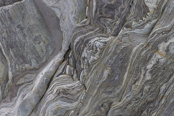 Geological fold with wavy layers of limestone and quartzite rocks on a cliff.
