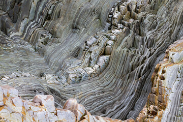 Geological fold with Wavy layers of limestone and quartzite rocks on a cliff