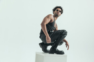 casual man squatting on the chair and flexing his muscles