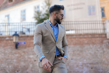 sexy bearded man with sunglasses looking to side and walking