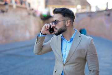 sexy bearded businessman in suit talking on the phone and looking to side