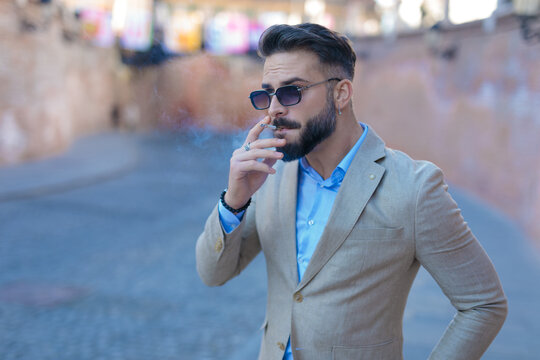 sexy businessman in suit looking to side and smoking cigarette