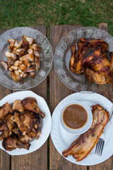 Plates of Lechon Manok or roasted chicken and Liempo or grilled pork belly, popular Filipino food served outside at a bench with gravy.