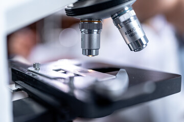 Scientist analyzing microscope slide at laboratory. Young woman technician is examining a histological sample, a biopsy in the laboratory of cancer research