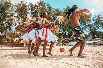 Kenyan people dance on the beach with typical local clothes