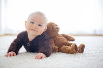 Little cute baby boy, dressed in handmade knitted brown teddy bear overall