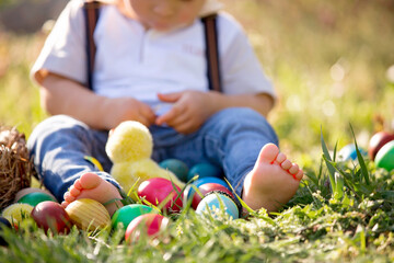 Sweet toddler boy with bunny ears, egg hunting for Easter, child and Easter day traditions