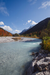 Fototapeta na wymiar Herbststimmung am Gebirgsfluss Rißbach im Rißtal in den Tiroler Alpen mit Blick auf Kiesbänke im Bach und Bergen im Hintergrund 