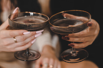 Glasses with champagne in female hands, close-up
