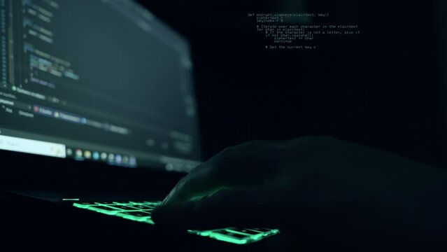 male programmer writes program code on a laptop. close-up. night