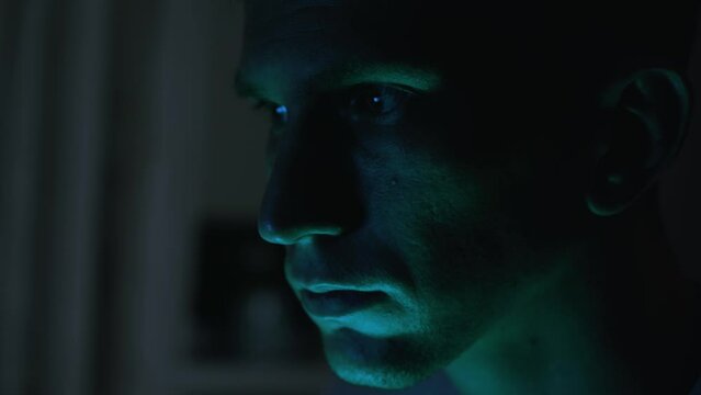 Portrait of a male hacker. nervous look. close-up. green light.