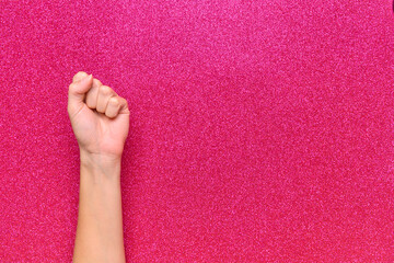 woman's fist on pink bright background - obrazy, fototapety, plakaty