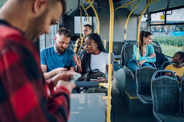 Multiracial friends talking and using a smartphone while riding a bus in the city