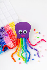 Funny octopus made of beads and pipe cleaners with different colorful and materials for DIY art activity for kids. Cute children's crafts, creativity and hobby. Development of fine motor skills