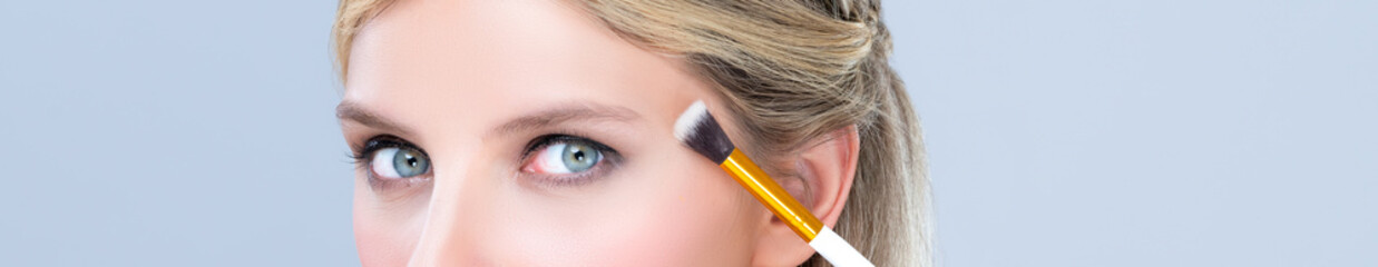 Closeup beautiful girl with flawless applying alluring eye shadow makeup with eyeliner brush....
