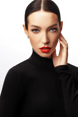 Fototapeta na wymiar pretty girl with red lips in black turtleneck hold a hand by the face