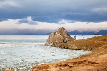 Beautiful view of Cape Burkhan on Olkhon Island on a cloudy spring day. Lake Baikal during the ice...