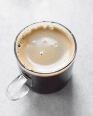 Espresso in a glass cup on a marble tray, foamy top of coffee