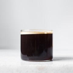Espresso in a glass cup on a marble tray, foamy top of coffee