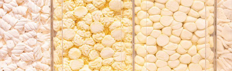 Lot of Pastel yellow marshmallows in a shop window. Food texture.